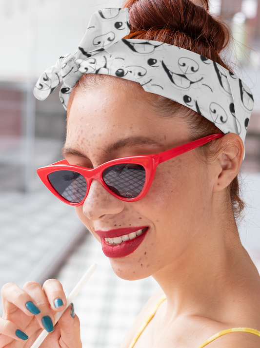 Woman smiling wearing red glasses with Nico Inspired all-over print bandana tied on her head
