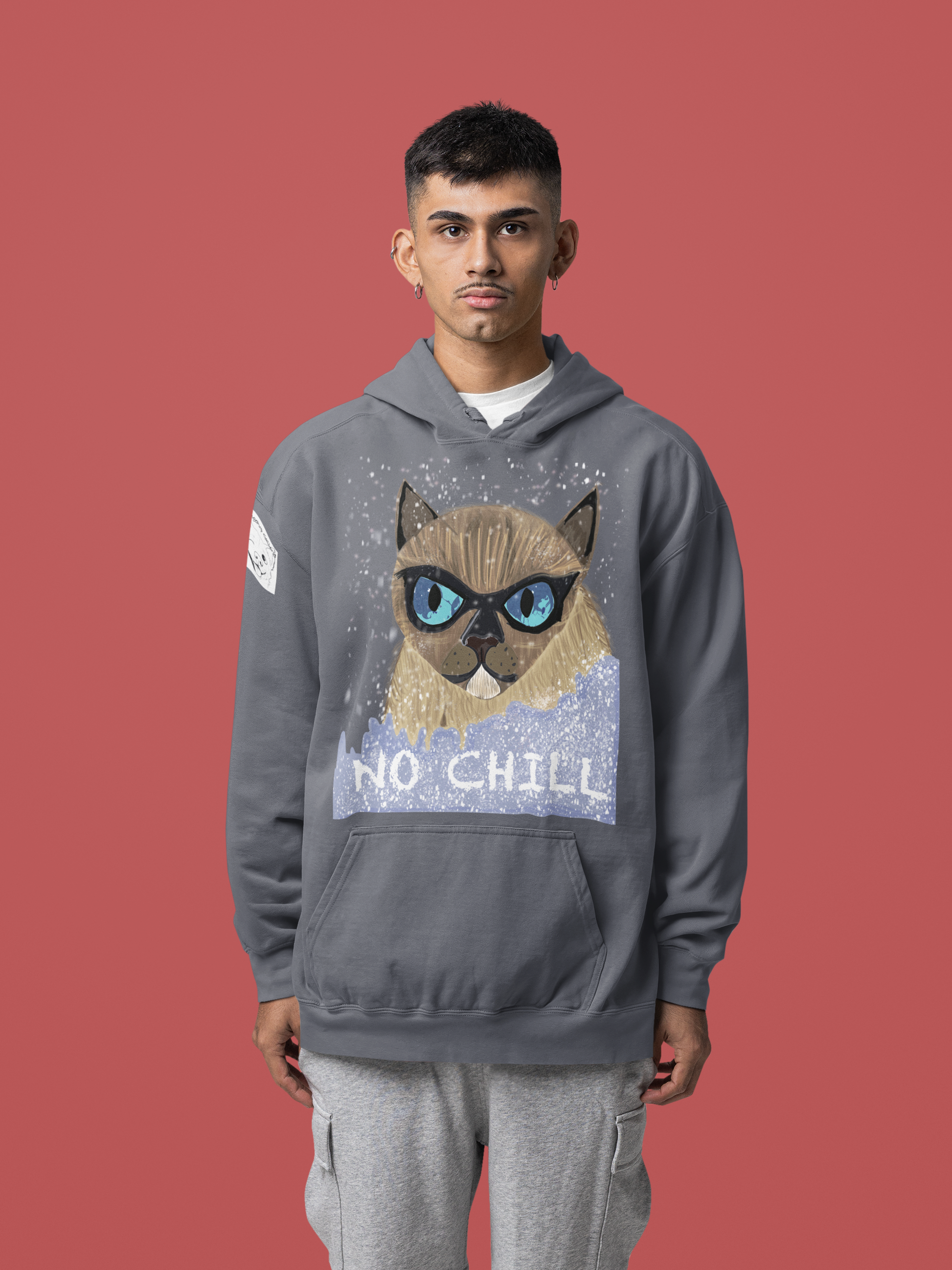 Man with short hair wearing denim colored No Chill Cat hoodie standing against red background