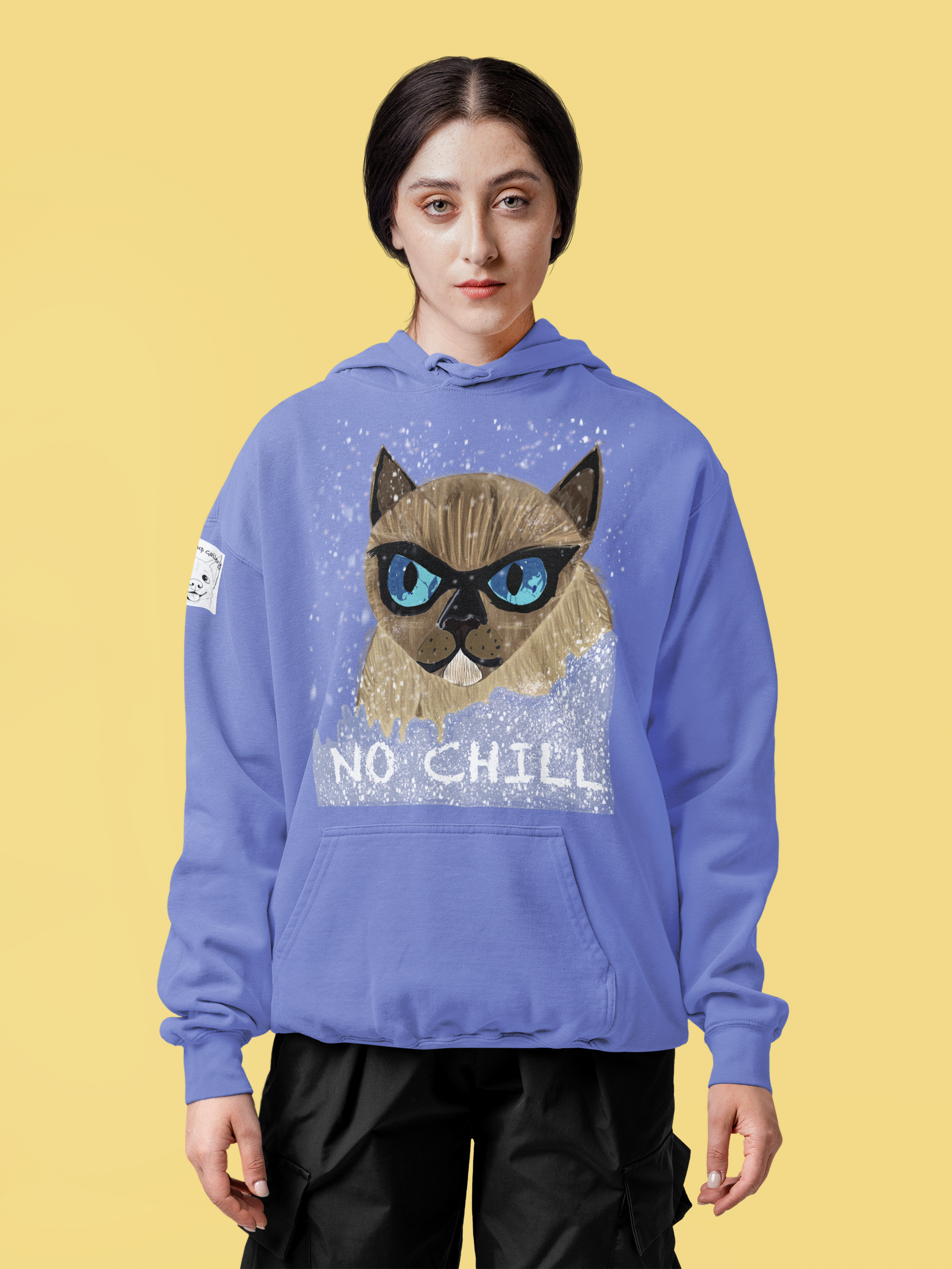 Woman with dark hair wearing flo blue No Chill Cat hoodie standing against yellow background