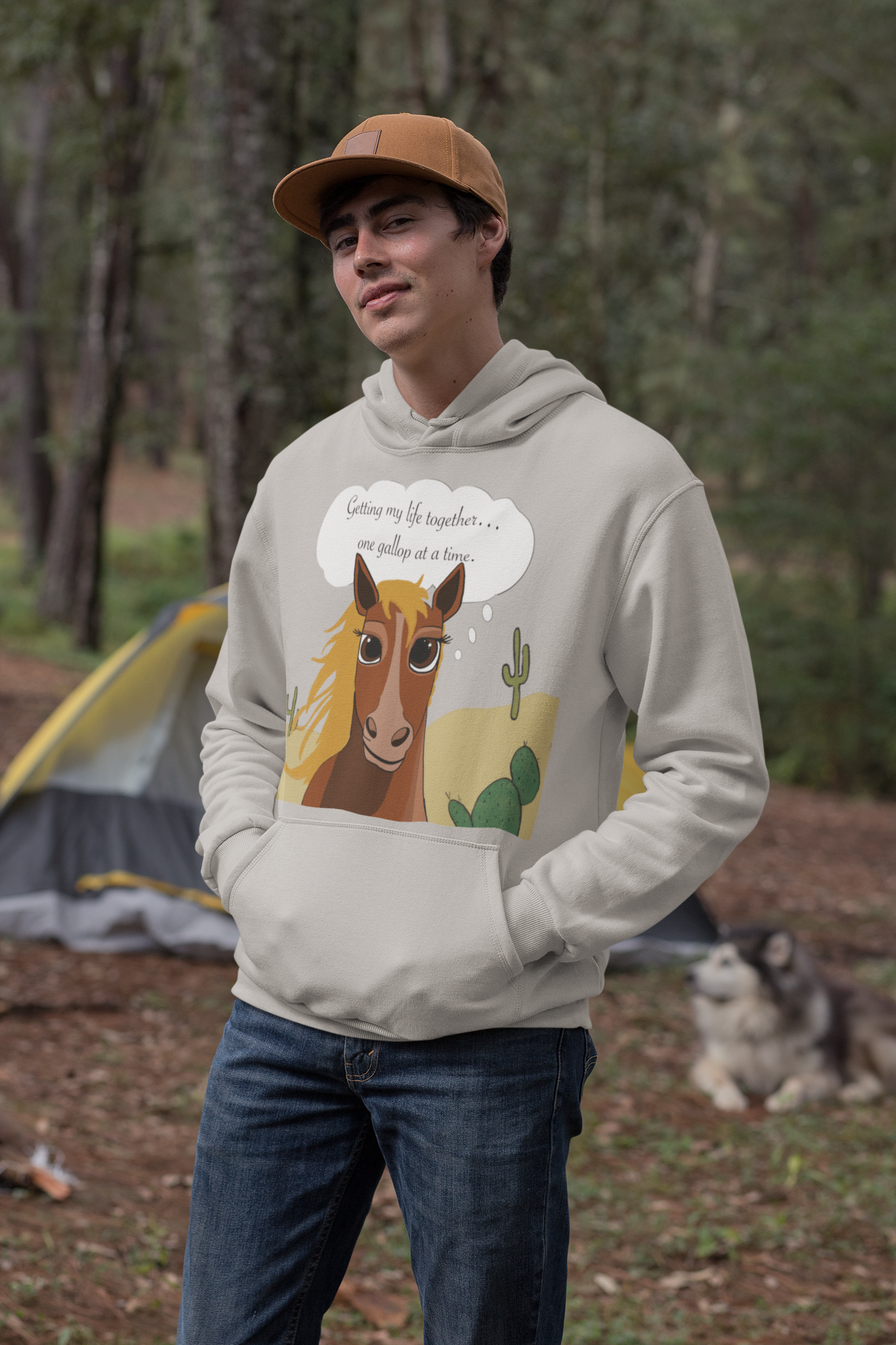 Man wearing carbon grey One Gallop at a Time hoodie standing in forest with dog nearby