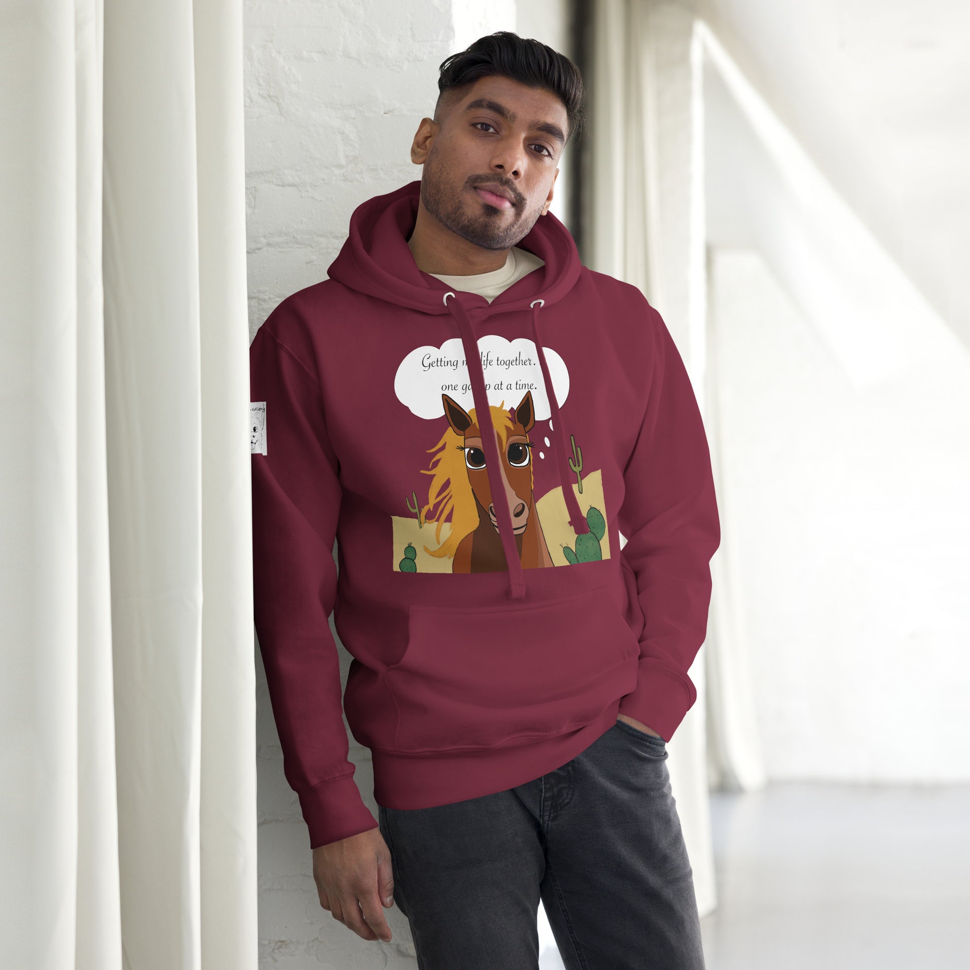 Man wearing maroon One Gallop at a Time hoodie posing indoors against white background