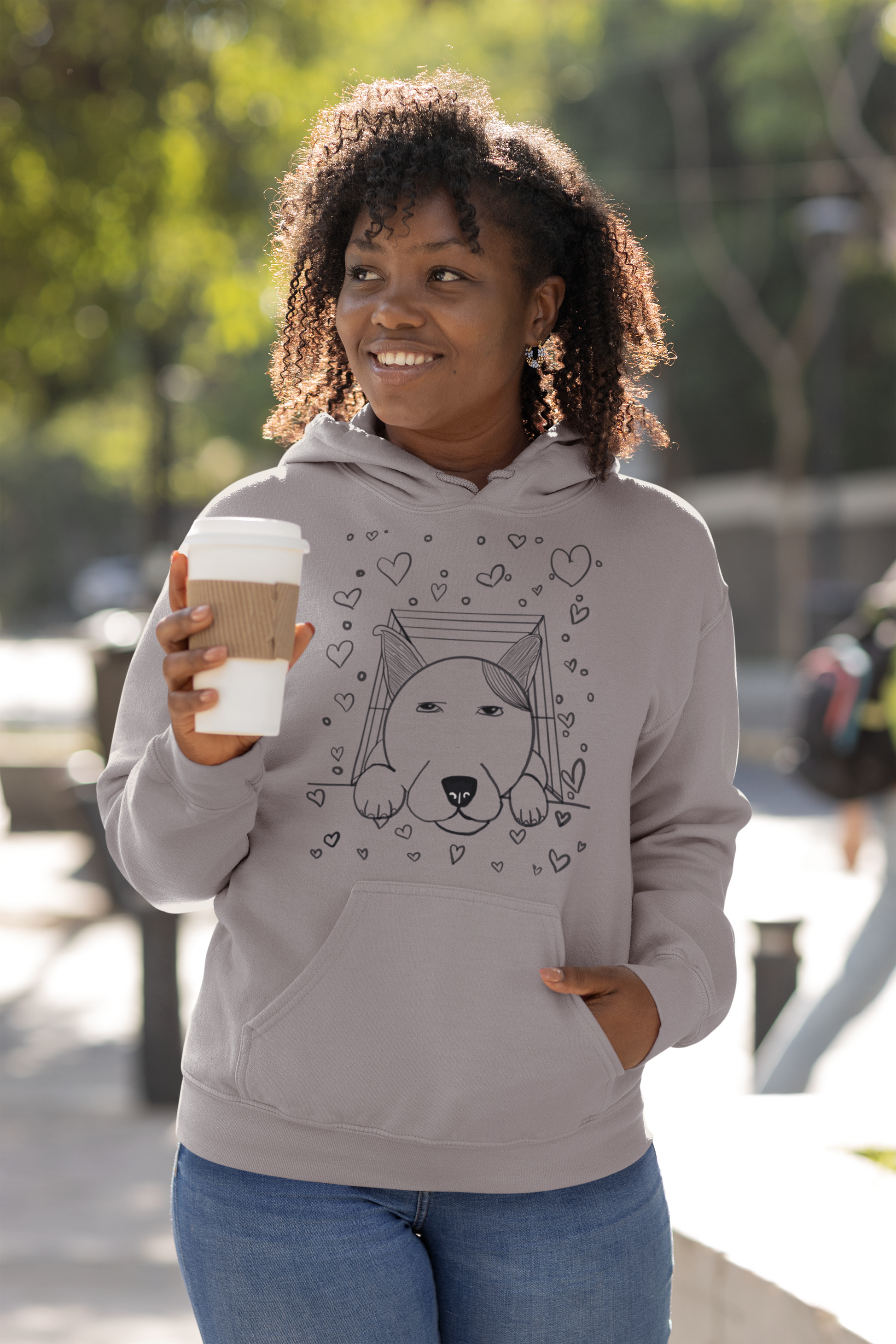Woman with curly hair wearing sport grey "Pup Love" hoodie with dog in box and hearts illustration – GrungePup Vet Chaos cute vet tech apparel