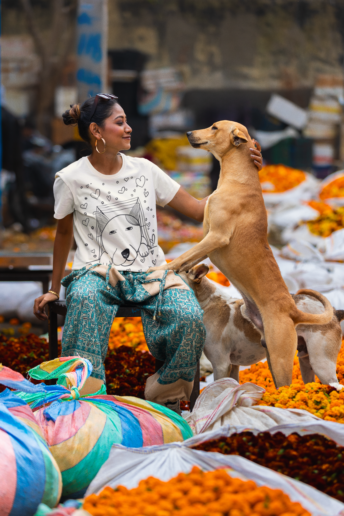 Woman sitting with dogs at market wearing vintage white "Pup Love" t-shirt with dog illustration and hearts – GrungePup Vet Chaos pet parent humor apparel