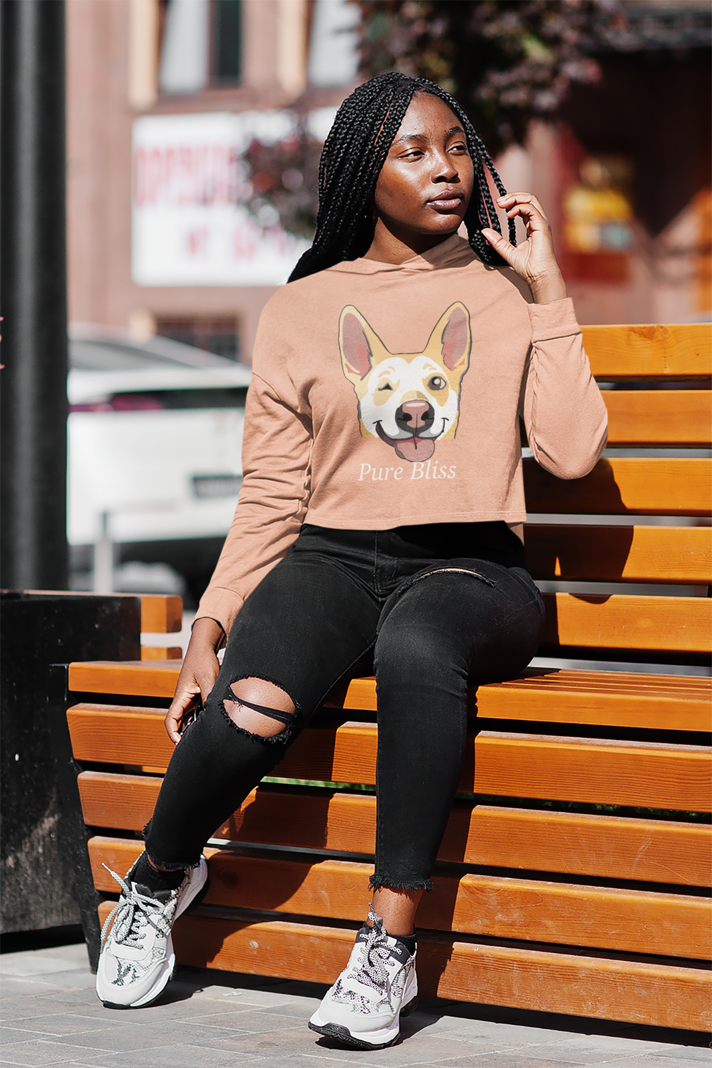 Woman sitting on bench wearing peach Pure Bliss Nico Face cropped hoodie