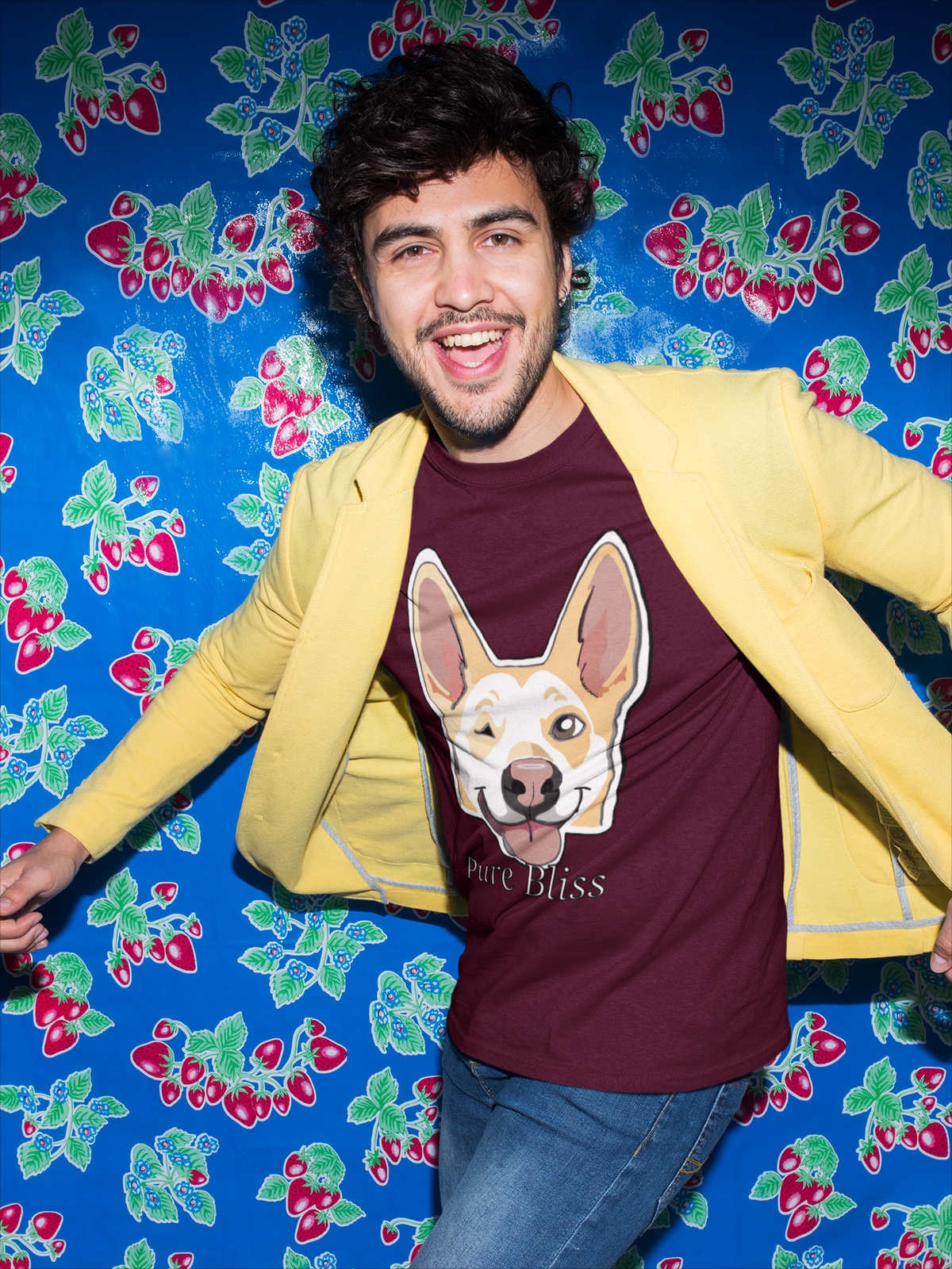 Smiling man in a yellow jacket over a maroon Pure Bliss t-shirt in front of a blue strawberry wall. Nico Inspired by GrungePup Gallery.