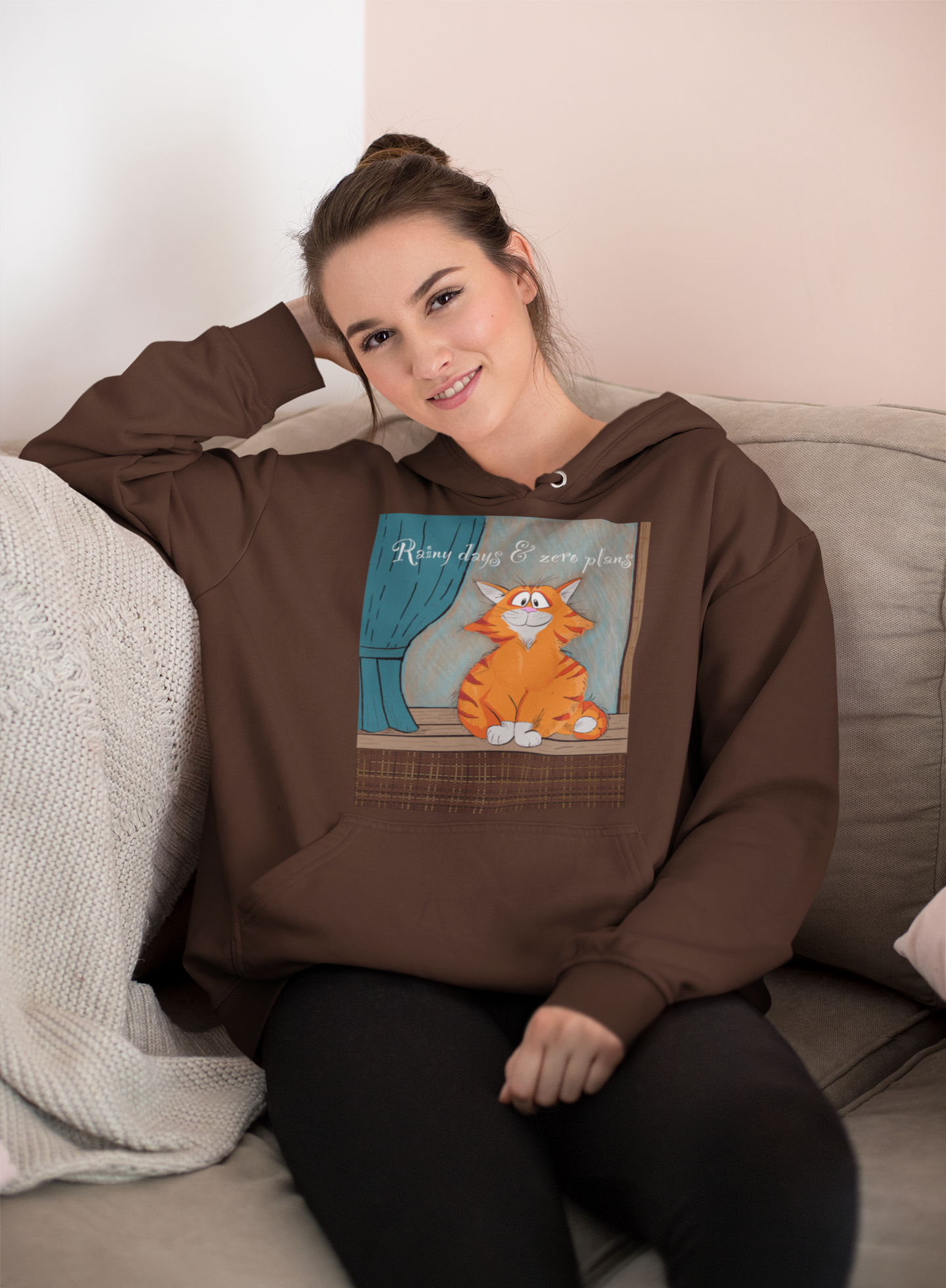 Woman relaxing on couch wearing dark chocolate brown Rainy Days & Zero Plans hoodie