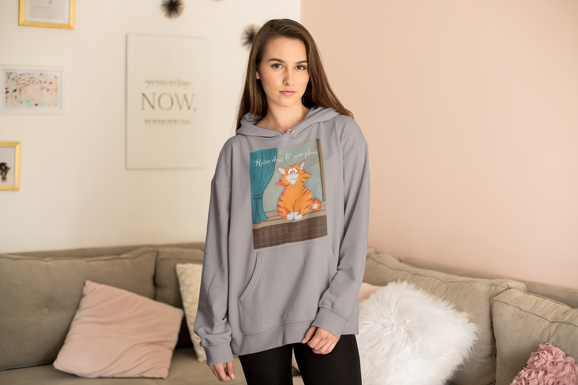 Woman standing in a room wearing sport grey Rainy Days & Zero Plans hoodie with cozy cat design