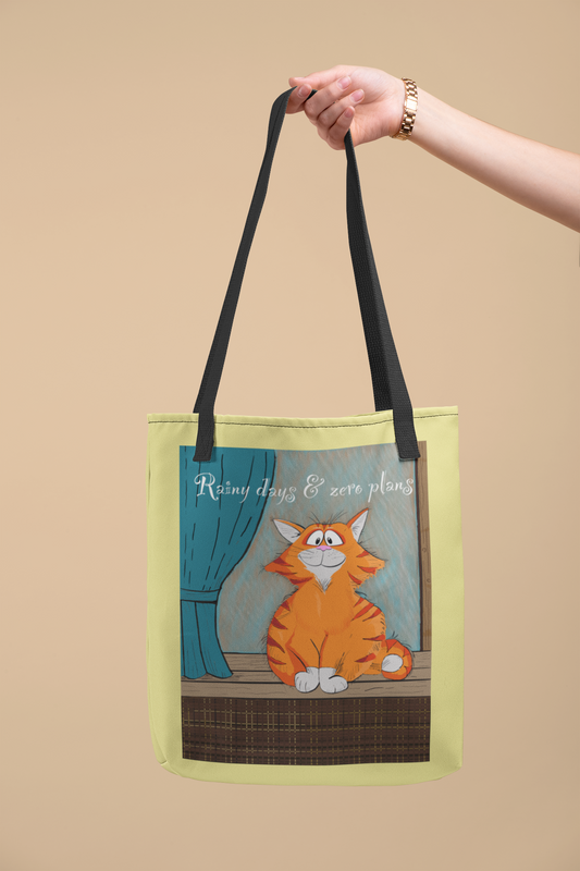 Hand holding lime green Rainy Days & Zero Plans cat tote bag with orange cat design and text "Rainy days & zero plans"