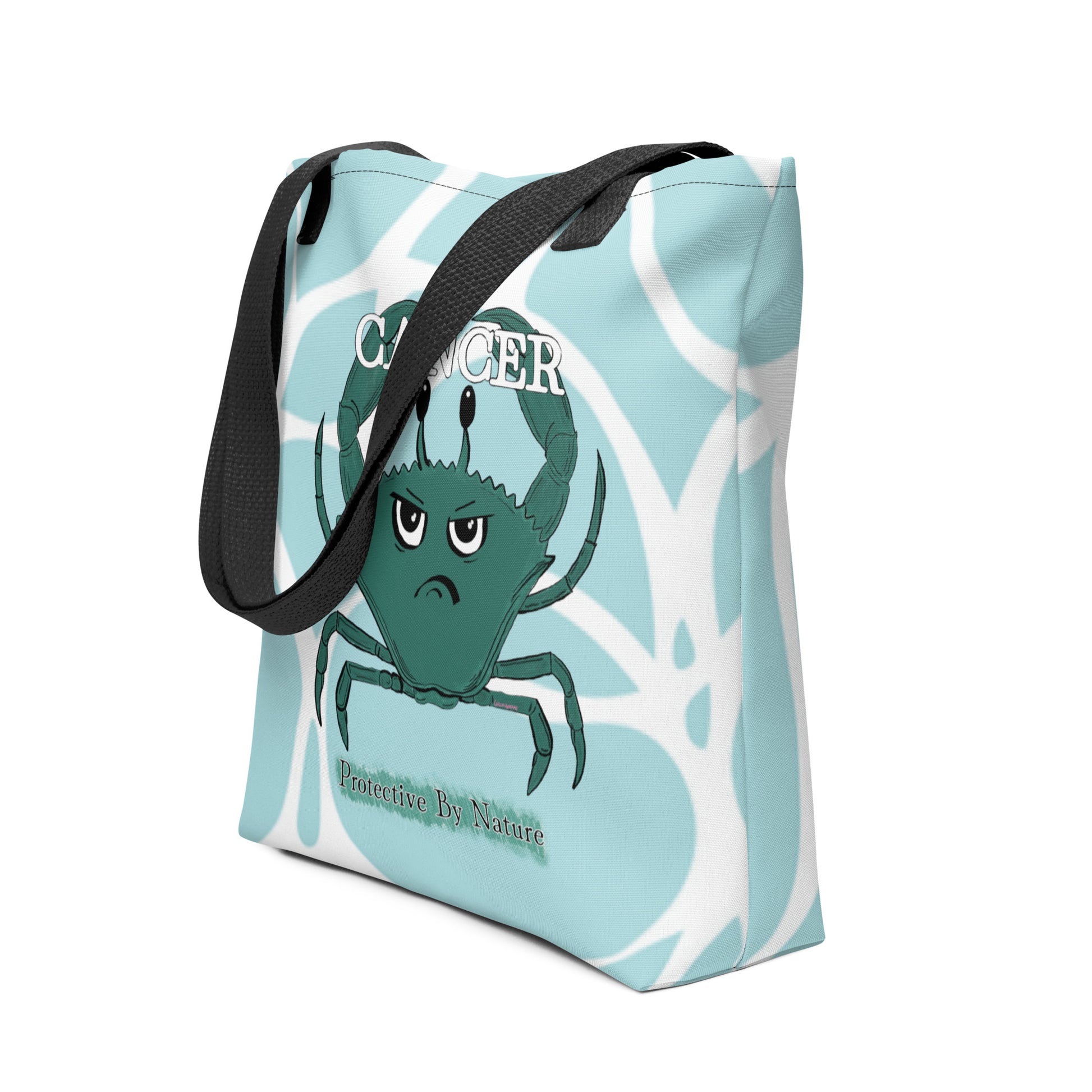 Side angle view of light blue all-over print Cancer "Protective By Nature" tote bag showing the crab design and black handles