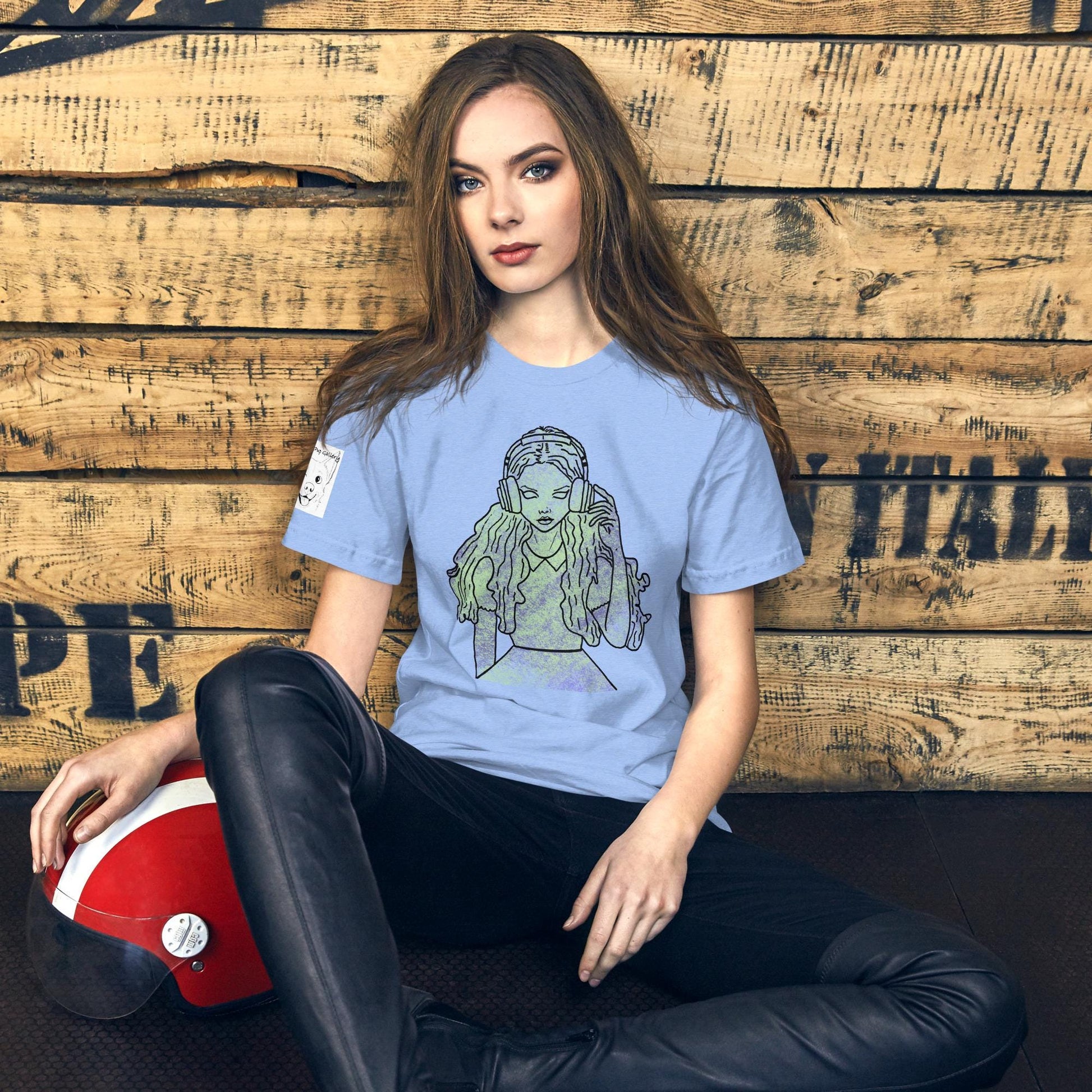 Lady sitting against wall wearing heather carolina blue Bella Canvas t-shirt with That Girl, Alice grunge-cute Wonderland design. Edgy and whimsical self-taught art for the ones who know the real adventure.