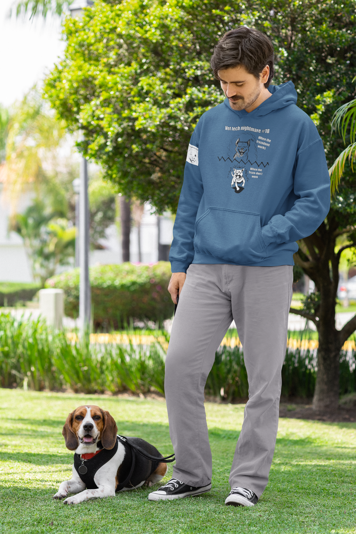 Man standing outdoors wearing an indigo blue Gildan 18500 hoodie with Vet Tech Nightmare #18 design showing the happy dog panel and the wild demonic dog panel.
