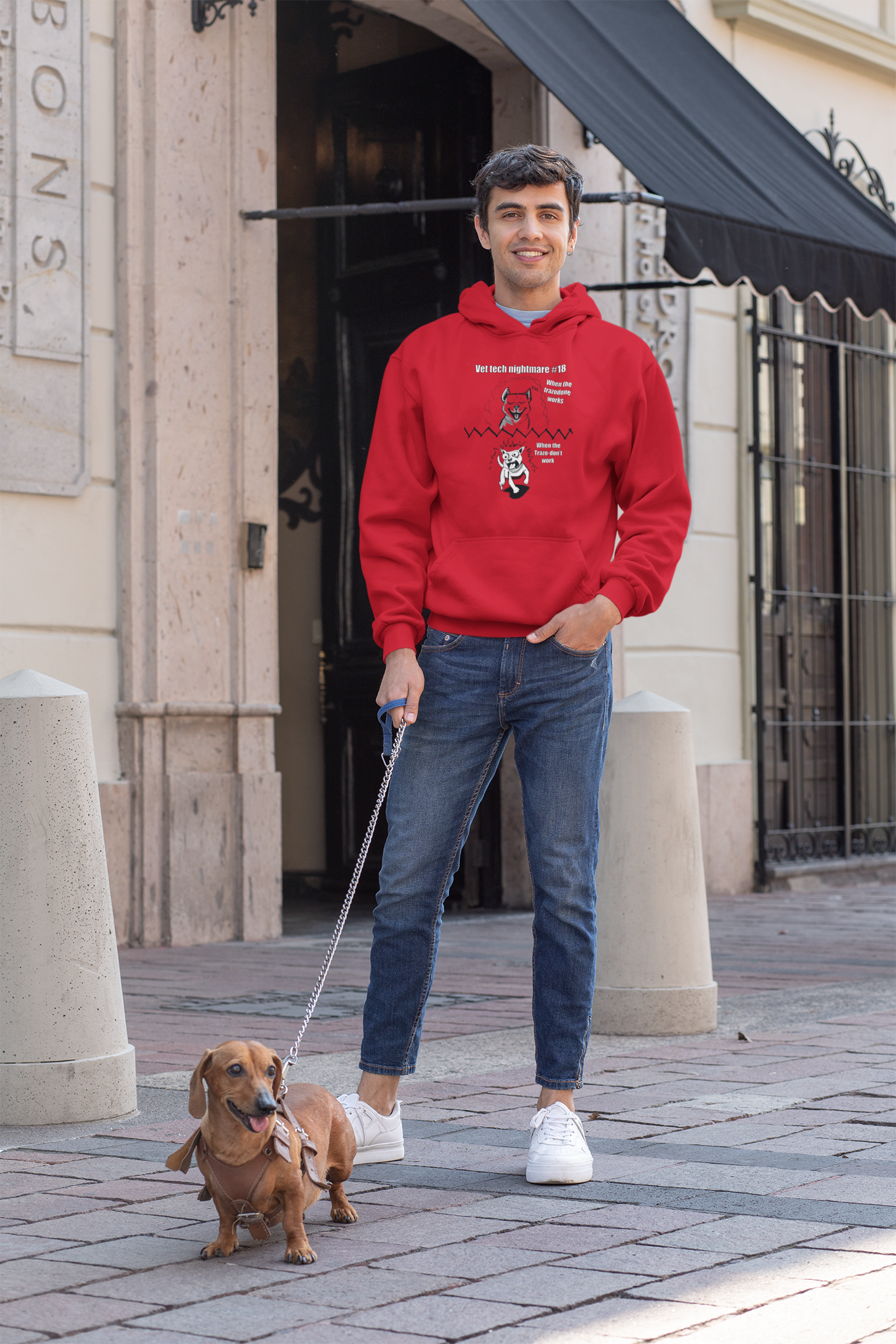 Man walking a dachshund on a leash while wearing a red Gildan 18500 hoodie with Vet Tech Nightmare #18 design.