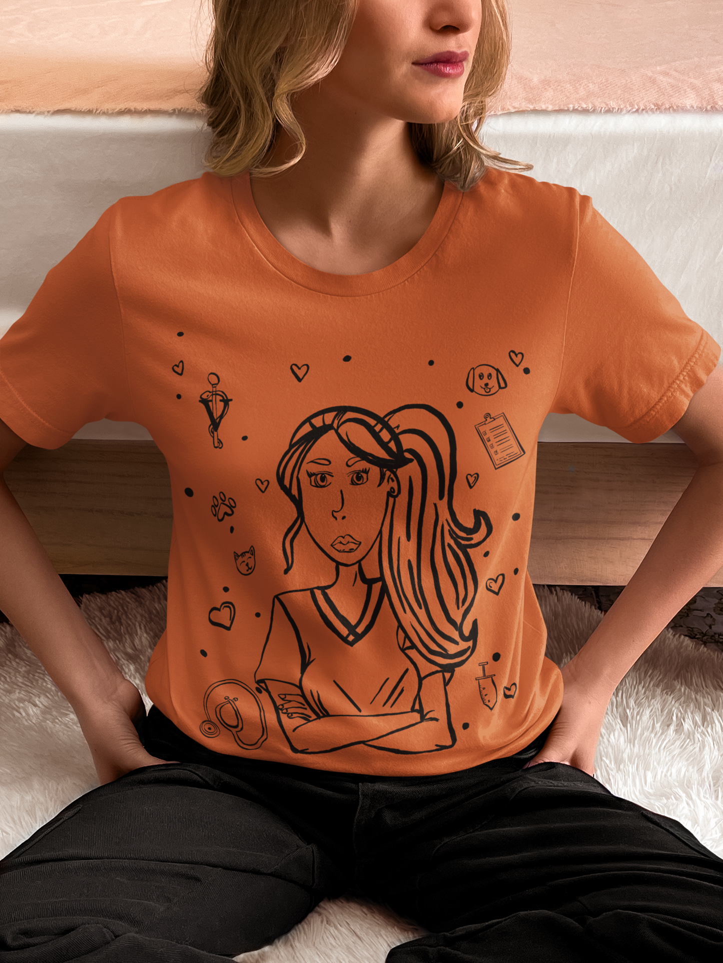 Woman with blonde hair sitting on a white fluffy surface near a bed, wearing a heather autumn Vet Vibe t-shirt with the darkened line-art vet girl design.
