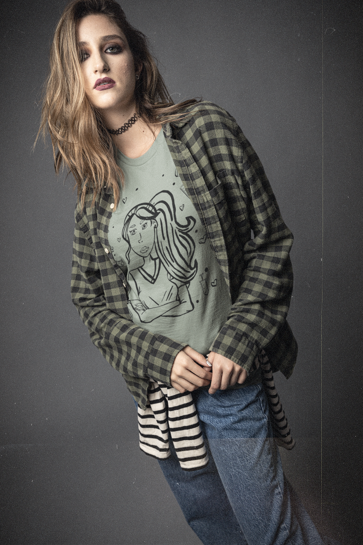 Woman with wavy hair wearing an open plaid flannel over a sage Vet Vibe t-shirt, posing with a serious expression against a dark background.