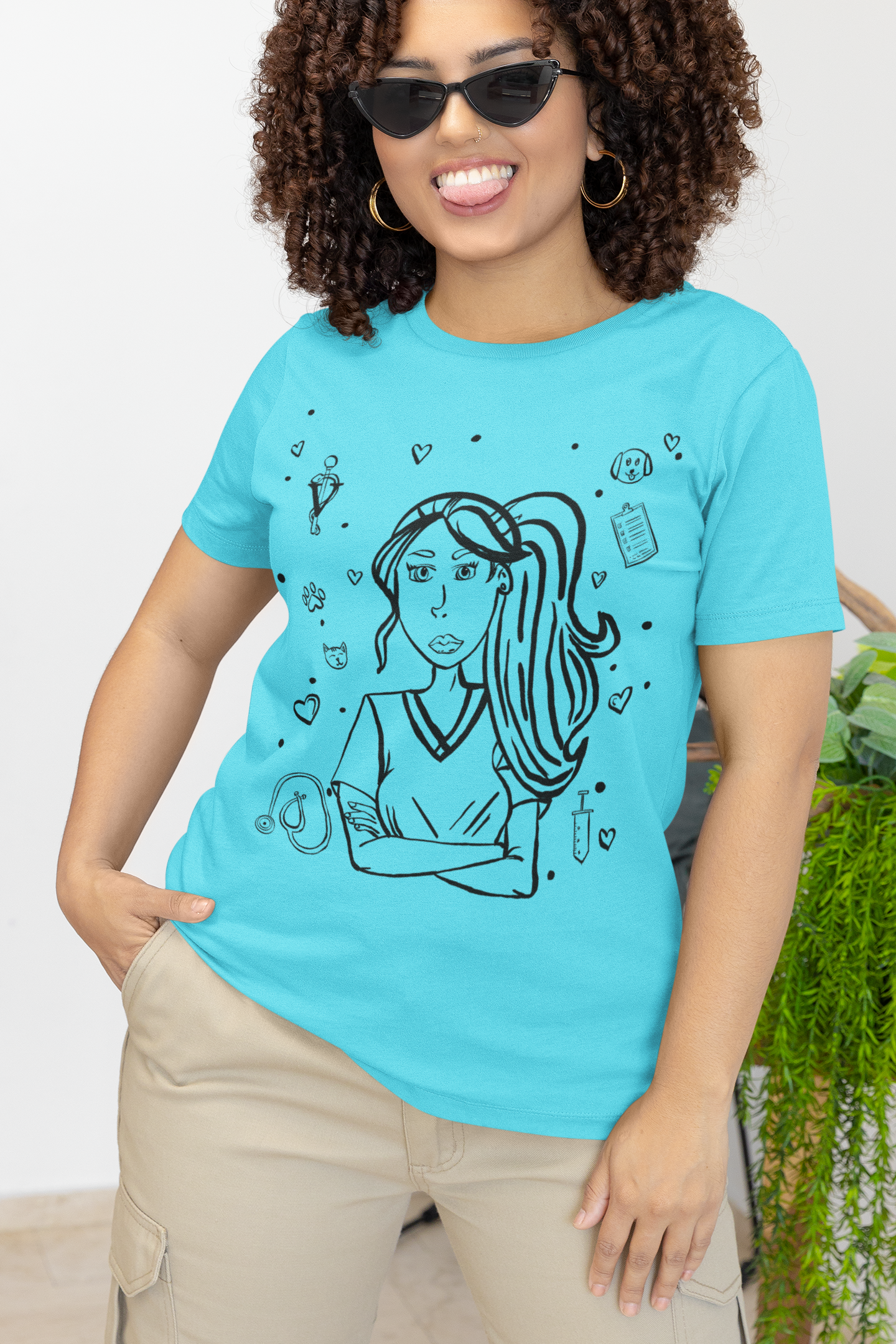 Woman with curly hair and sunglasses sticking her tongue out playfully while wearing a turquoise Vet Vibe t-shirt with the darkened line-art vet girl design.