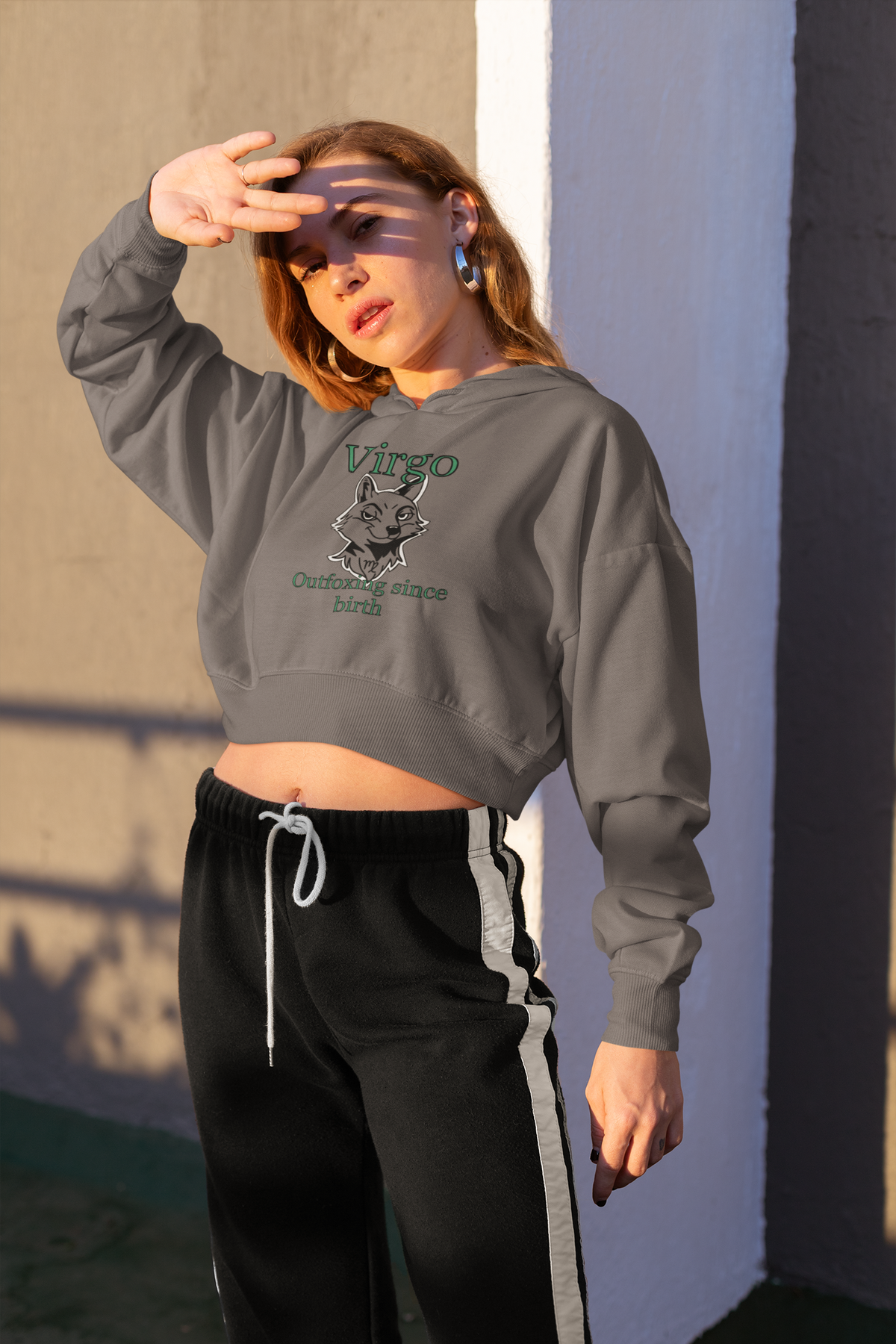 Woman standing in sunlight wearing a storm Bella + Canvas Virgo Outfoxing Since Birth cropped hoodie.