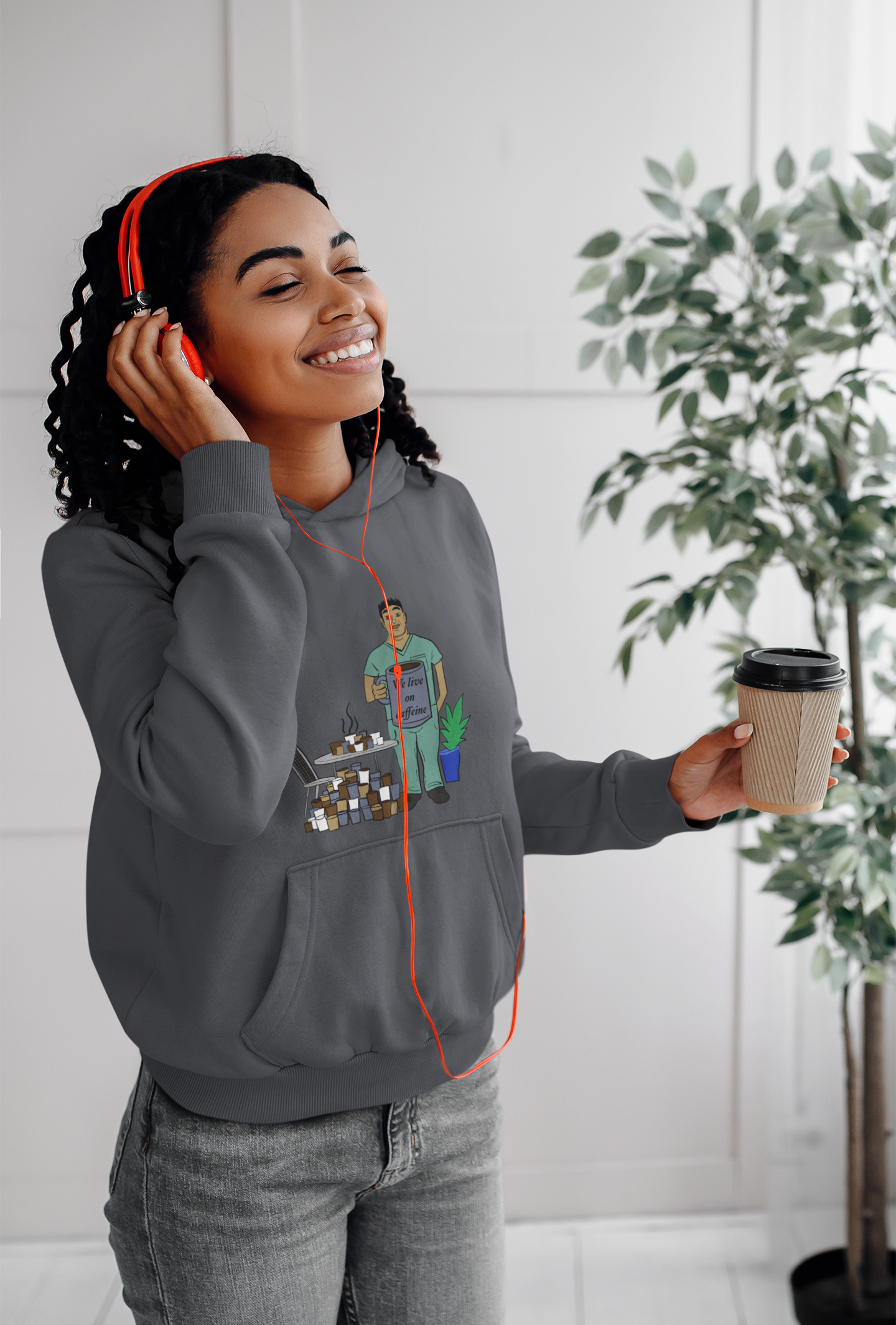 Woman with headphones wearing dark heather "We Live on Caffeine" hoodie with vet tech and coffee design – GrungePup Vet Chaos caffeine-fueled vet tech humor