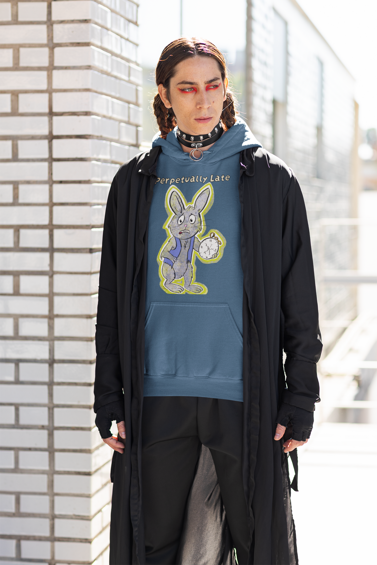Person with red eyeliner and a spiked choker standing by a white brick wall in an indigo blue White Rabbit Perpetually Late hoodie. GrungePup That Girl, Alice.