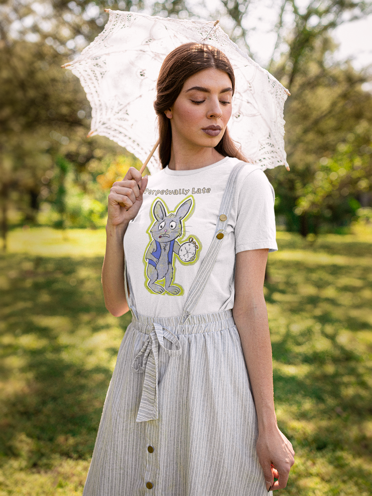 Woman in a white White Rabbit Perpetually Late t-shirt and striped overall dress holding a lace parasol in a grassy field. GrungePup That Girl, Alice.