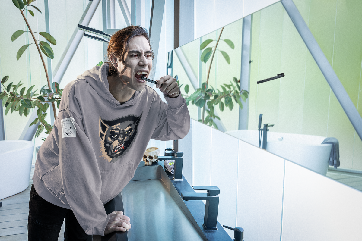 Man with vampire fangs brushing his teeth in a modern bathroom, wearing a sport grey Wolfman hoodie
