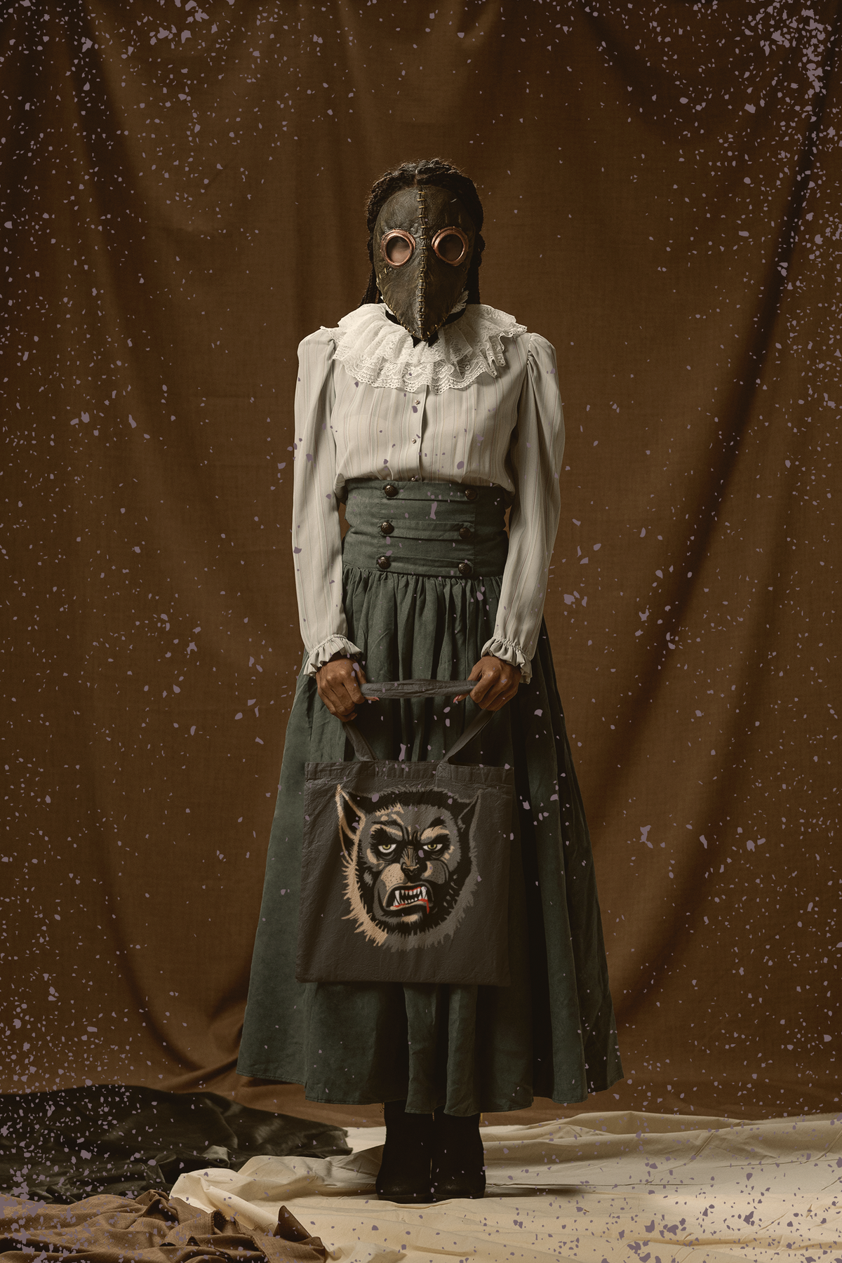 Woman in a vintage dress and plague-doctor mask holding the charcoal Wolfman tote bag, face-only Wolfman print with yellow eyes and bared teeth facing forward