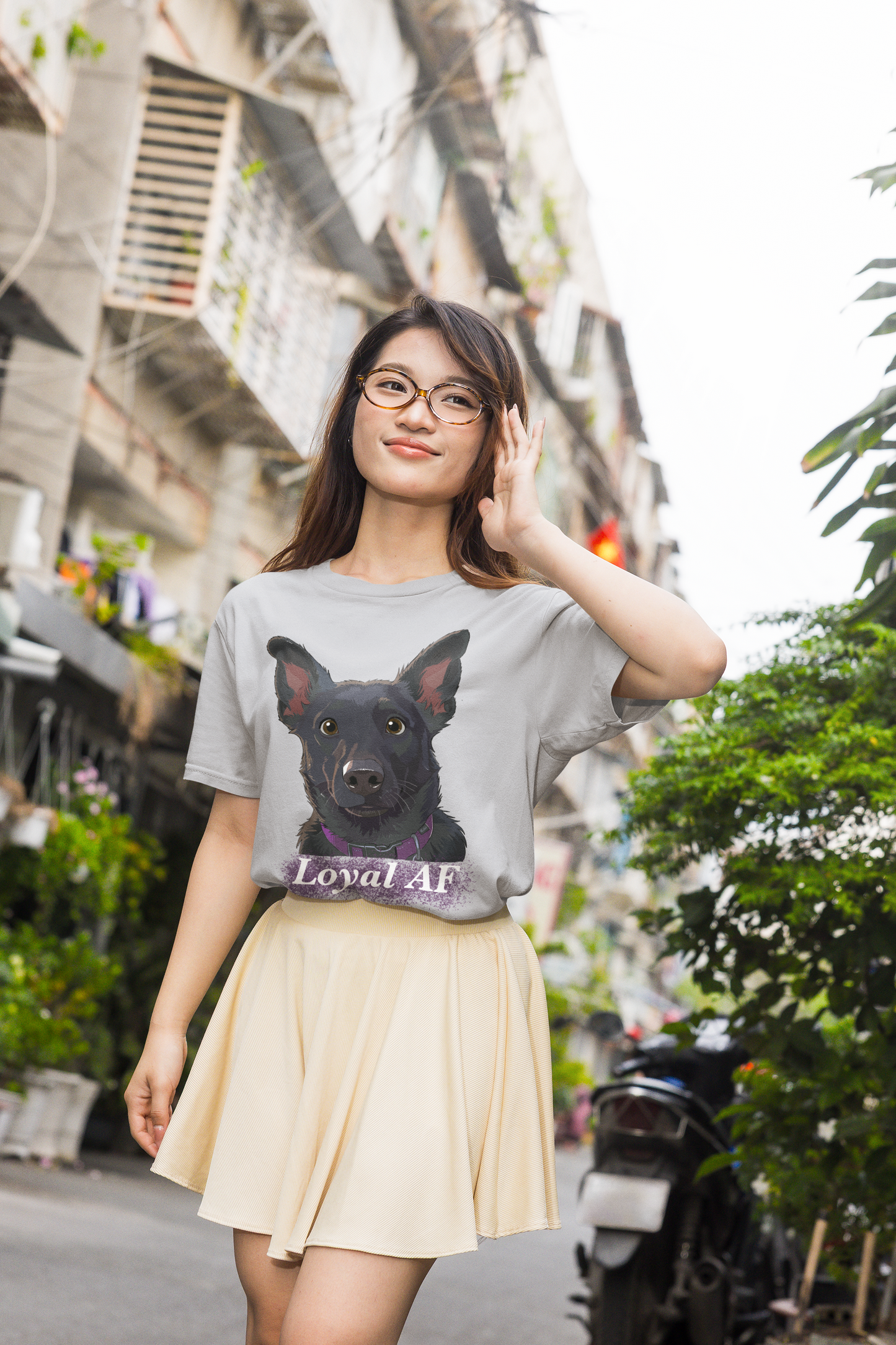 Young woman adjusting her glasses while wearing a sport grey t-shirt with Mathis Loyal AF portrait on city street