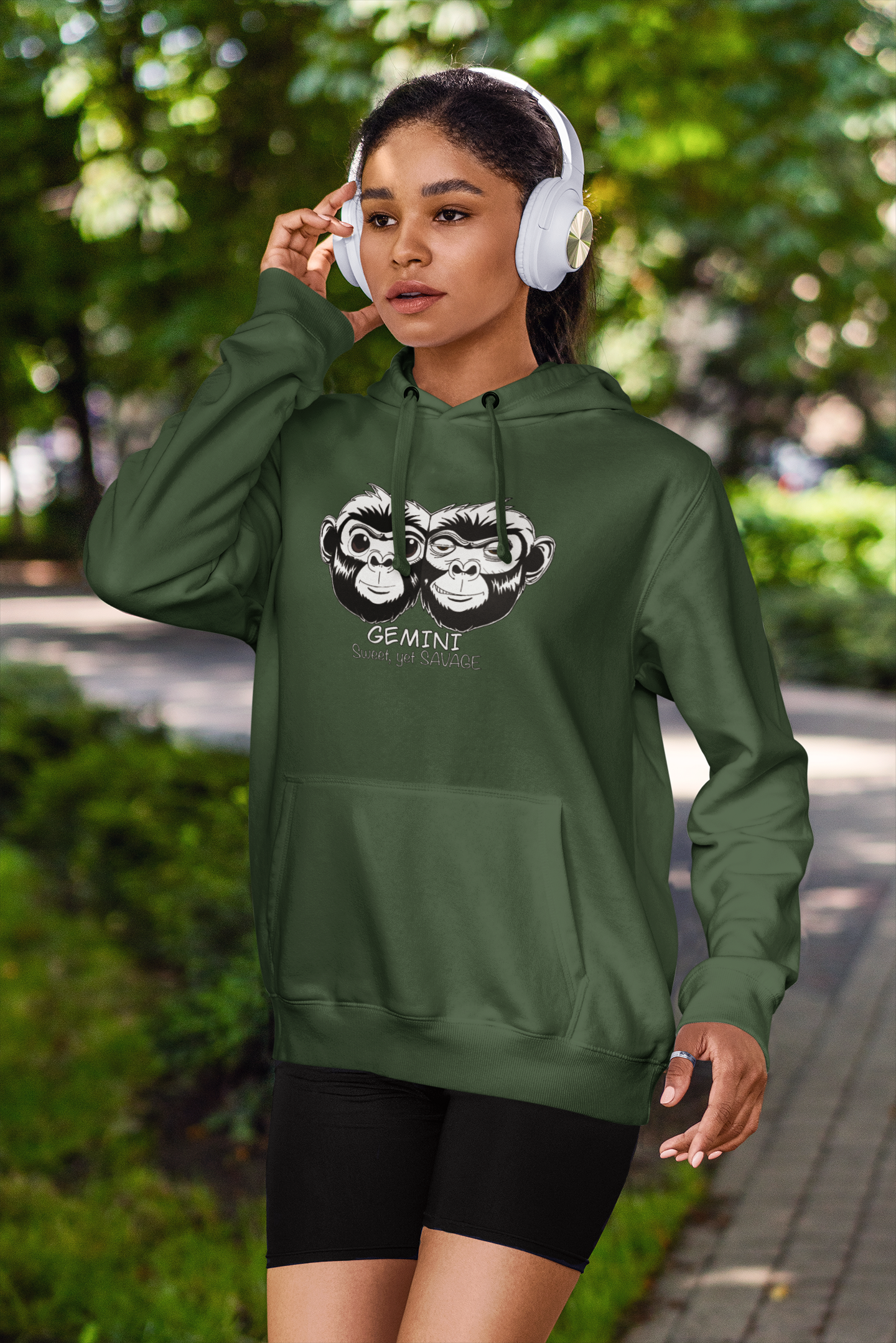 Woman jogging outdoors wearing a forest green Gemini Sweet Yet Savage hoodie and headphones