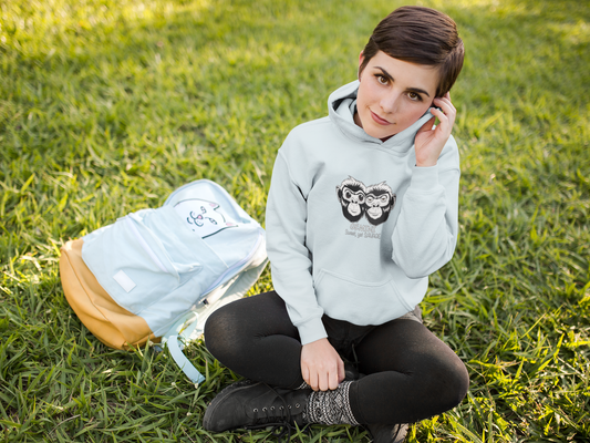 Woman sitting cross legged on grass looking up while wearing a sky blue Cotton Heritage Gemini hoodie