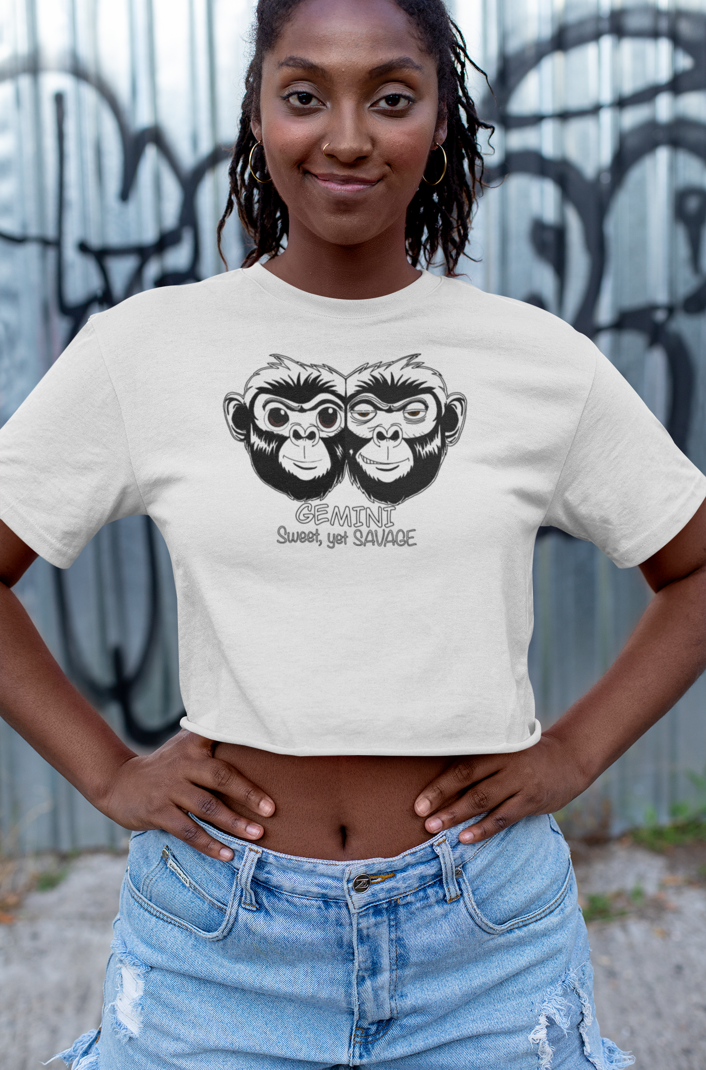 Woman standing confidently with hands on hips wearing a white cropped tee featuring the black and white Gemini monkey design