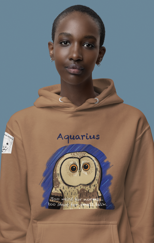 Woman posing against a blue background wearing a latte tan Cotton Heritage hoodie with the Aquarius Owl illustration by GrungePup