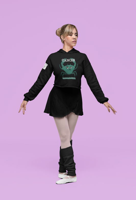 Woman in black cropped Cancer "Protective By Nature" hoodie dancing gracefully against a pink studio background