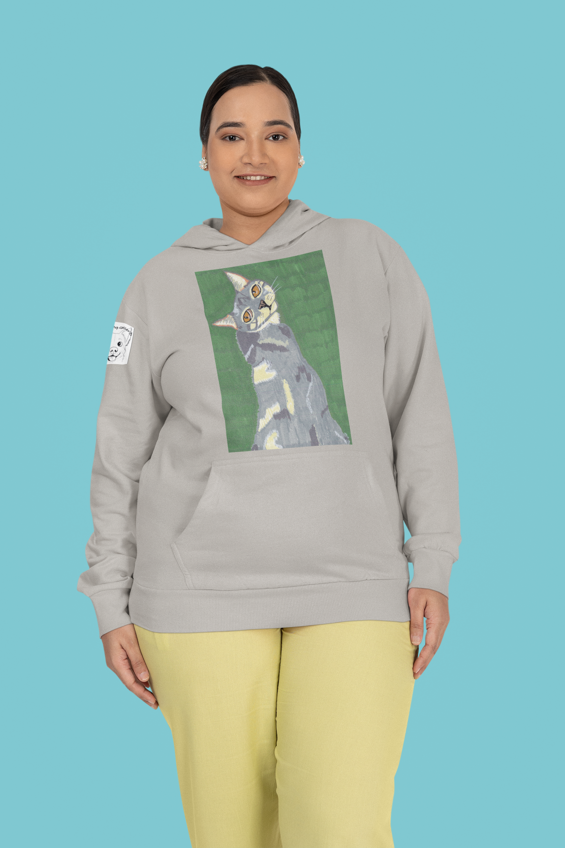 Woman standing in studio wearing a carbon grey Cotton Heritage hoodie featuring Mr. Grey cat portrait by GrungePup
