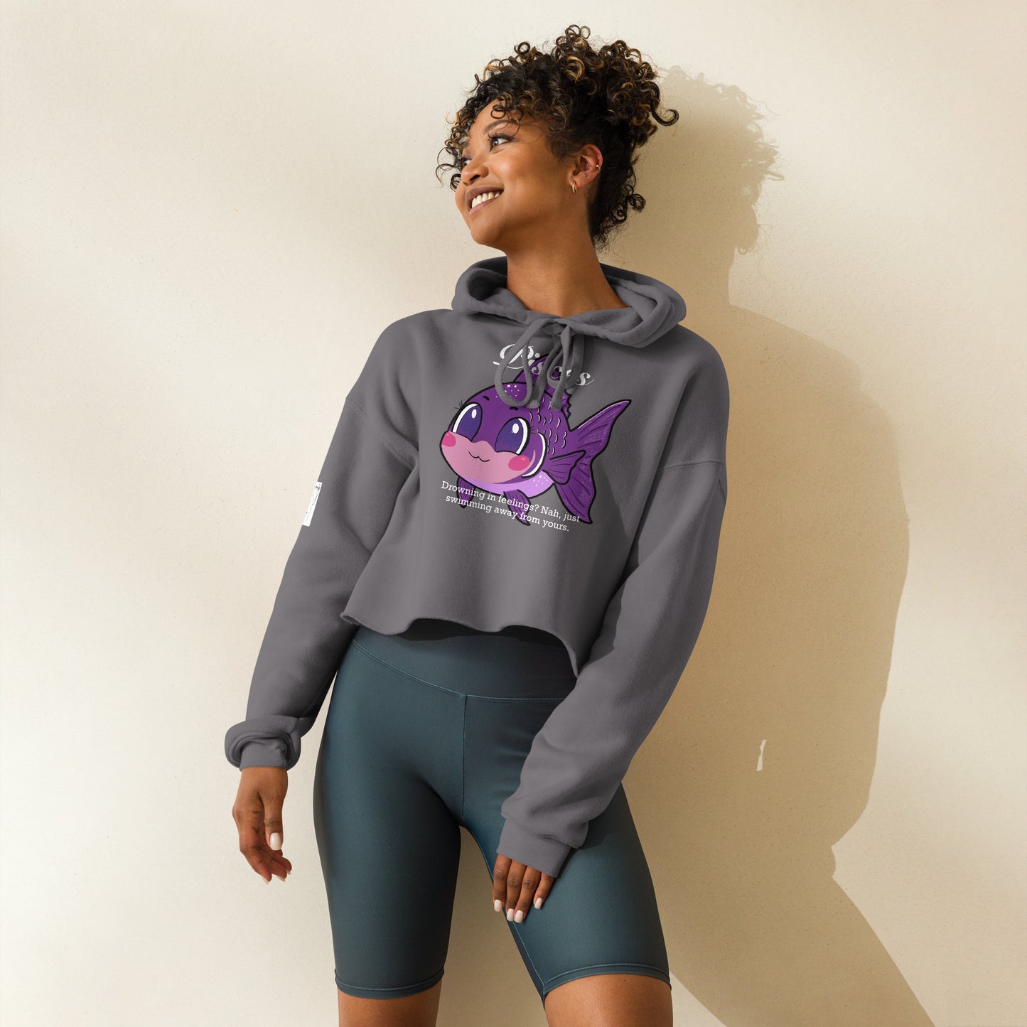 Woman in athletic wear and leggings wearing a Storm blue-gray Pisces cropped hoodie standing indoors