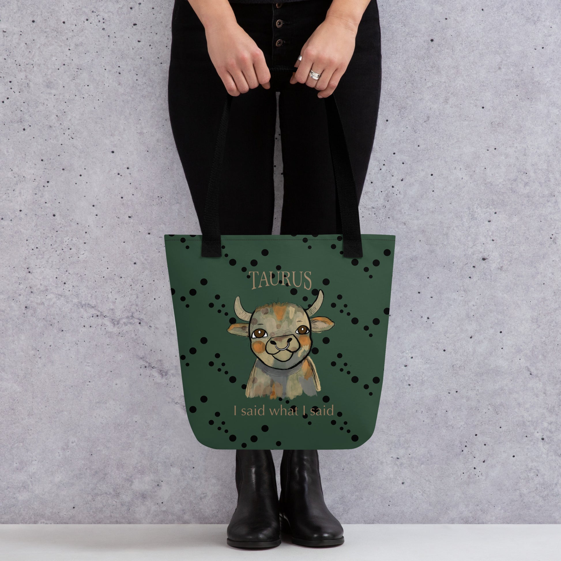 Woman wearing black pants holding a green Taurus Bull sarcastic zodiac all-over print tote bag
