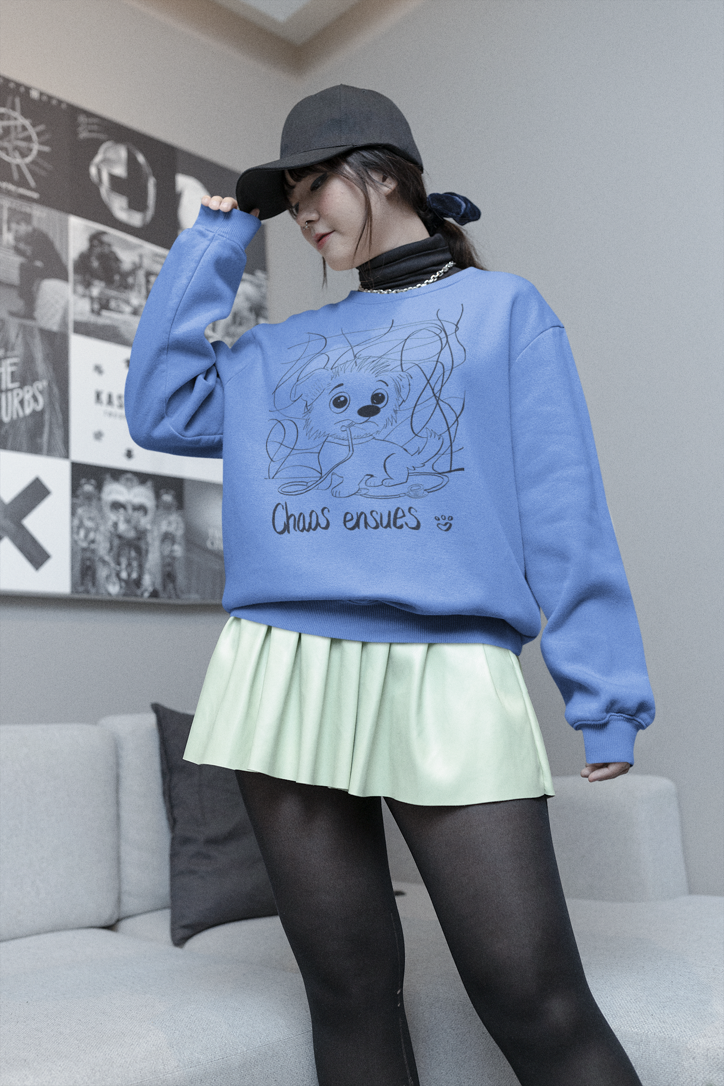 Woman with black cap and blue sweatshirt wearing Chaos Ensues crewneck in a casual pose