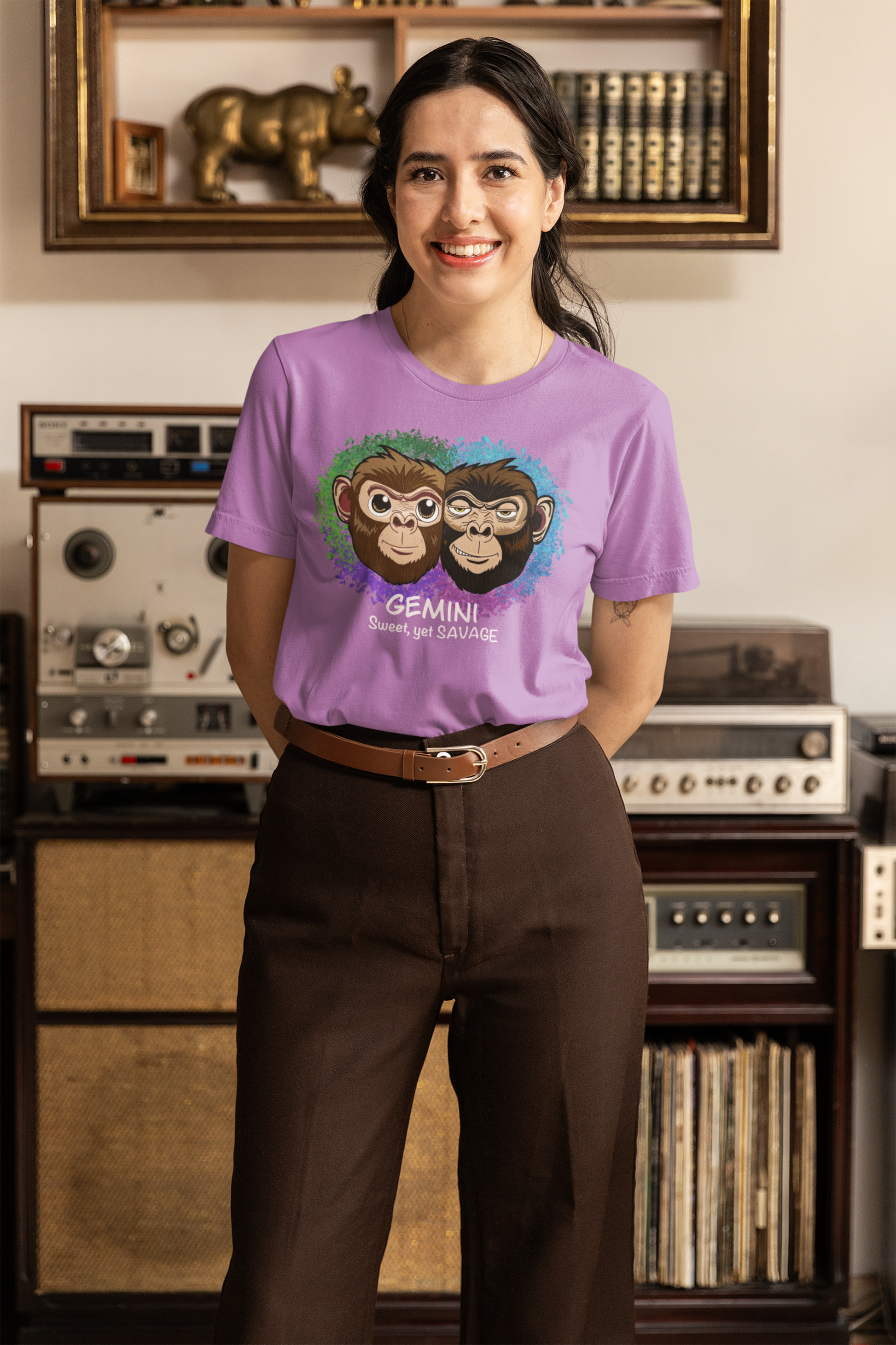 Smiling woman with dark hair wearing a heather team purple Gemini "Sweet, yet SAVAGE" t-shirt in front of vintage decor