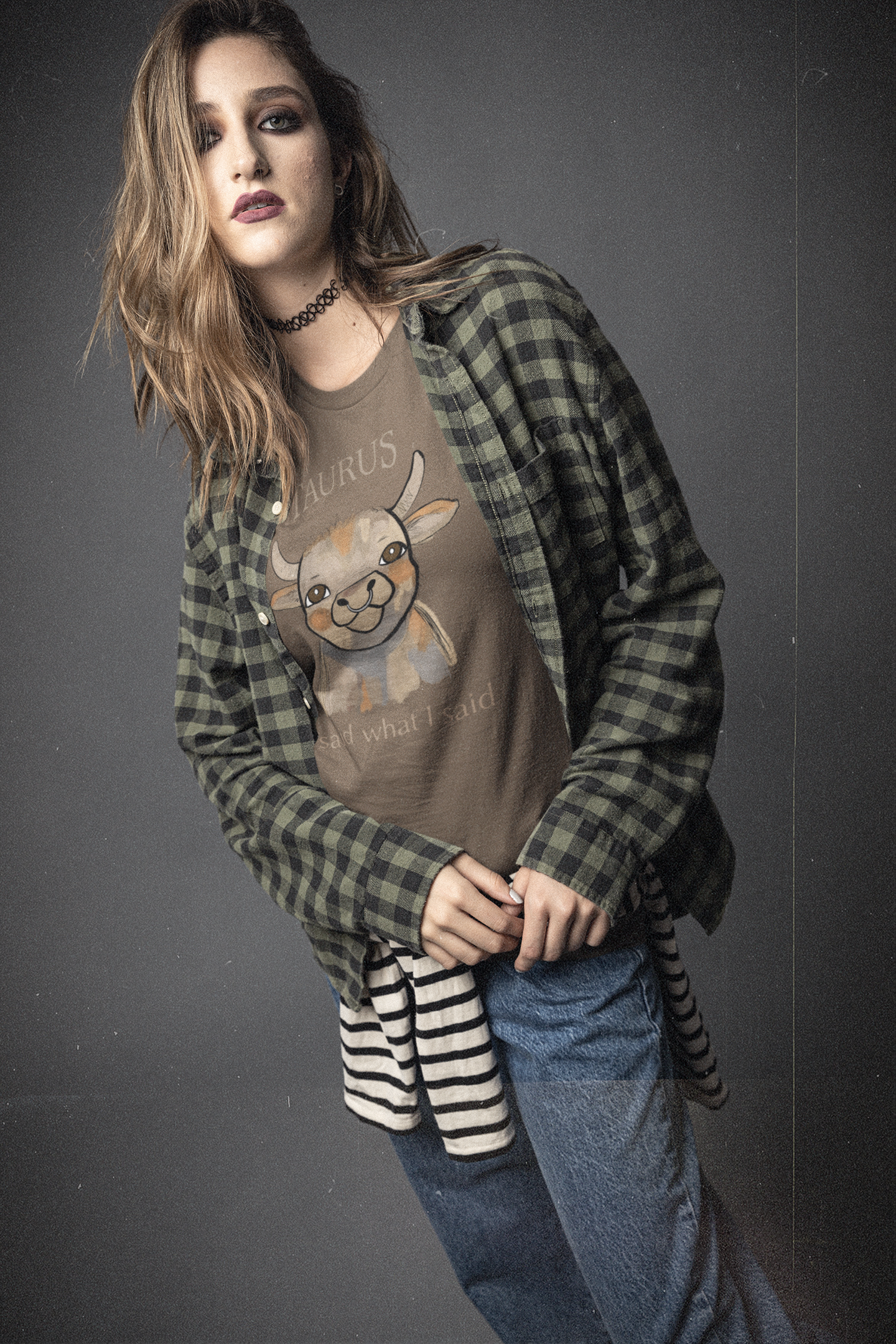 Serious woman with long hair in plaid flannel shirt wearing a heather brown Taurus Bull t-shirt