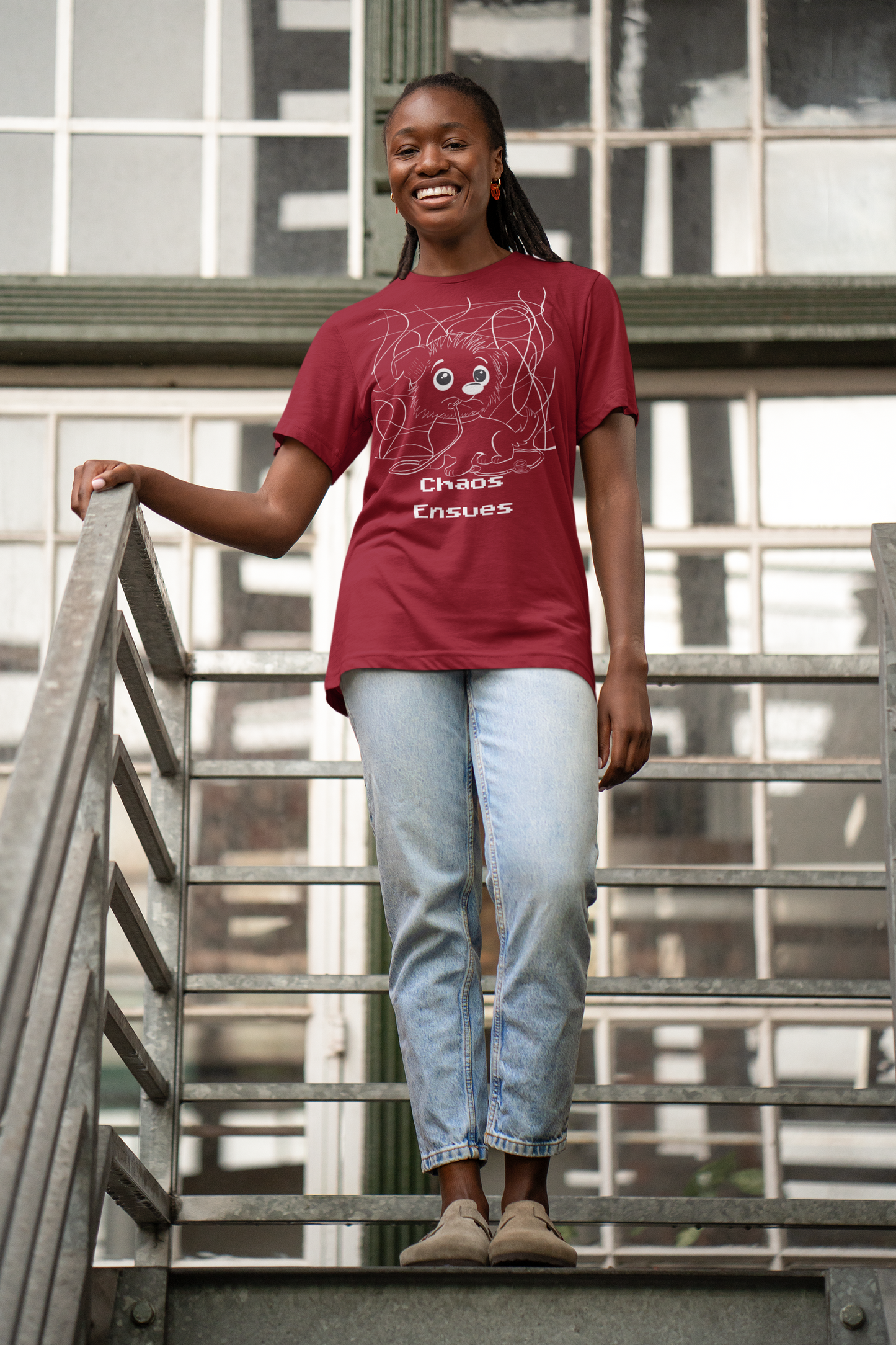 Smiling woman wearing red cardinal Chaos Ensues t-shirt on outdoor stairs
