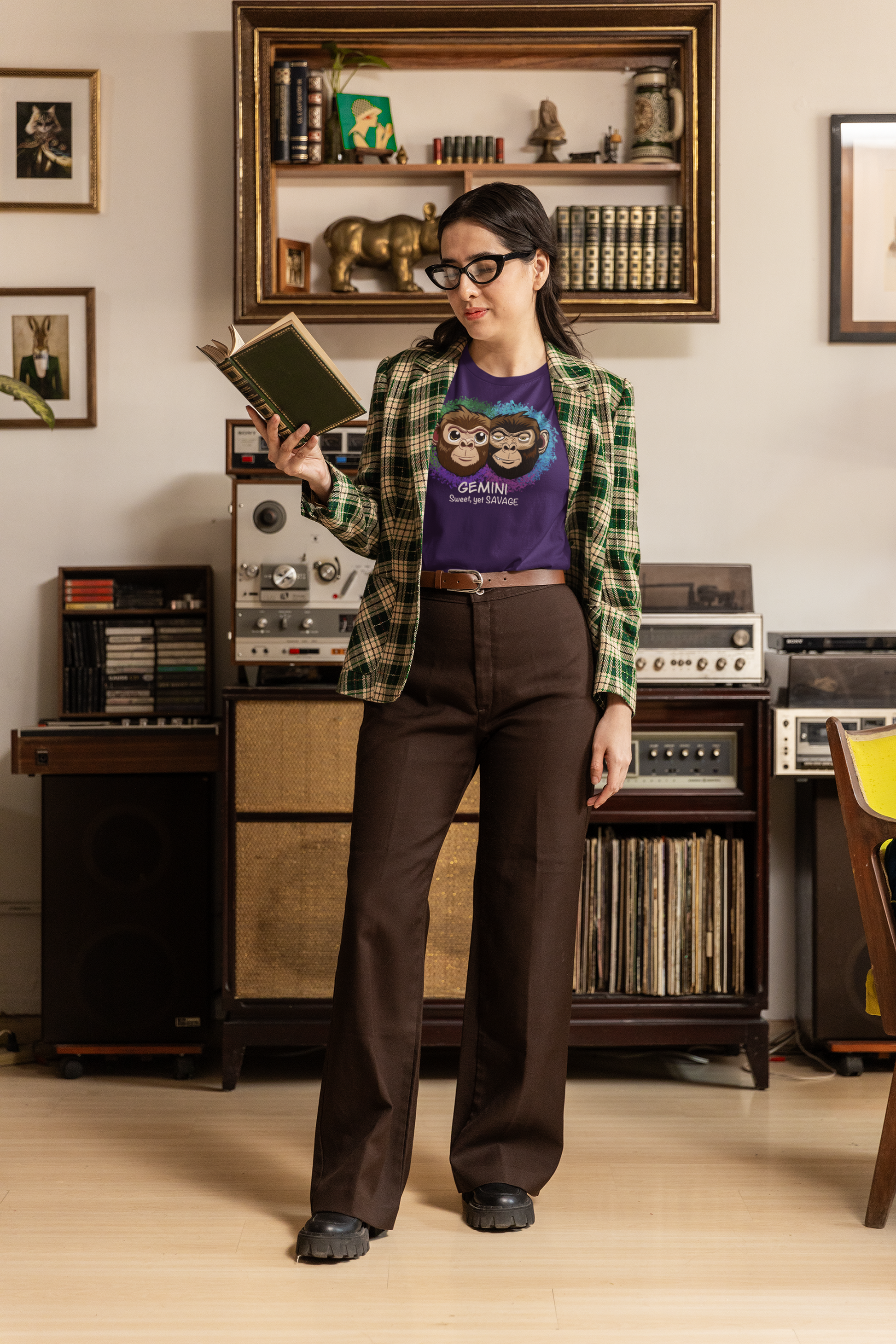 Woman with glasses reading a book while wearing a team purple Gemini "Sweet, yet SAVAGE" t-shirt in a vintage-inspired room