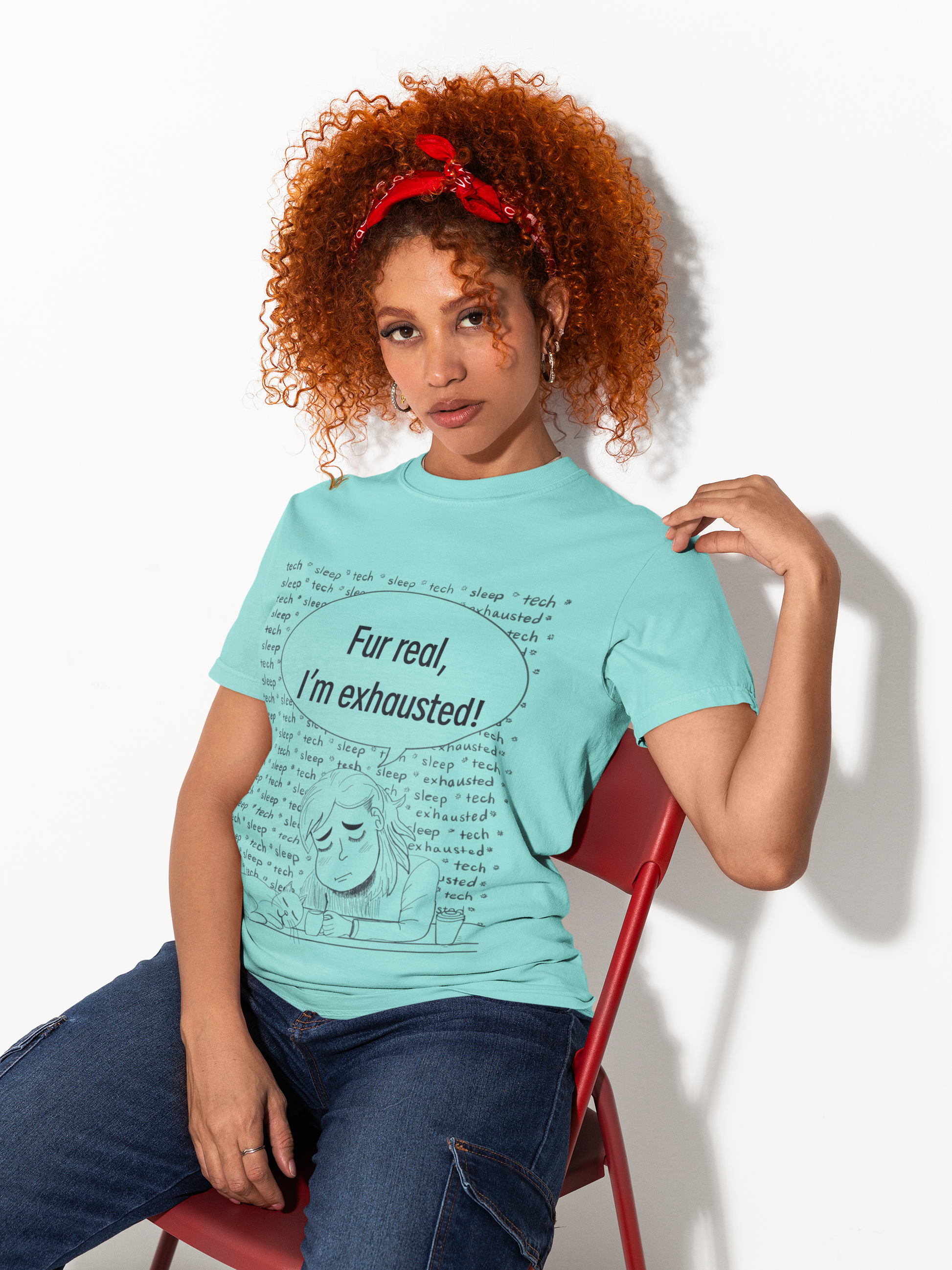 Woman with curly red hair and red bandana wearing a lagoon blue Fur Real, I'm Exhausted t-shirt sitting on a red chair