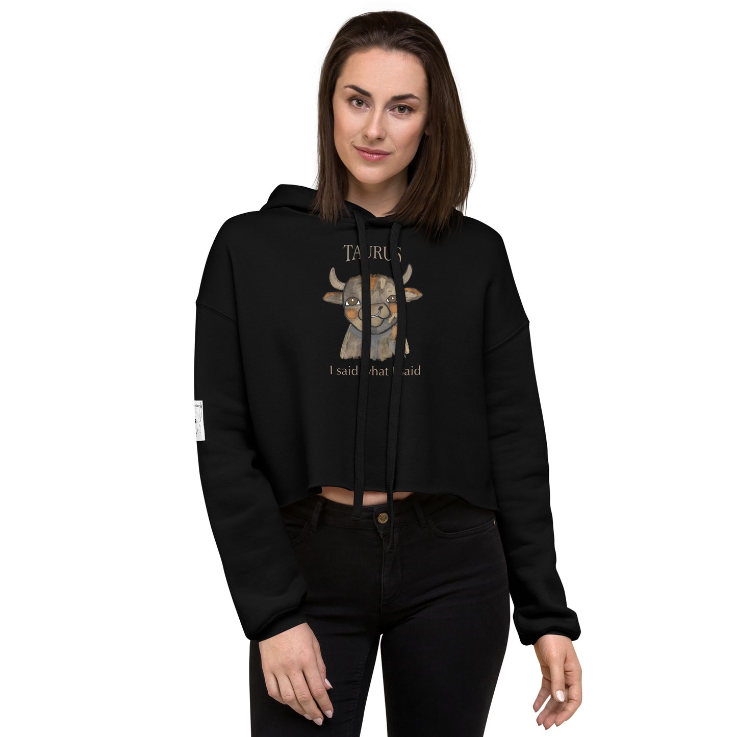 Woman standing against white background wearing a black Taurus I Said What I Said cropped hoodie