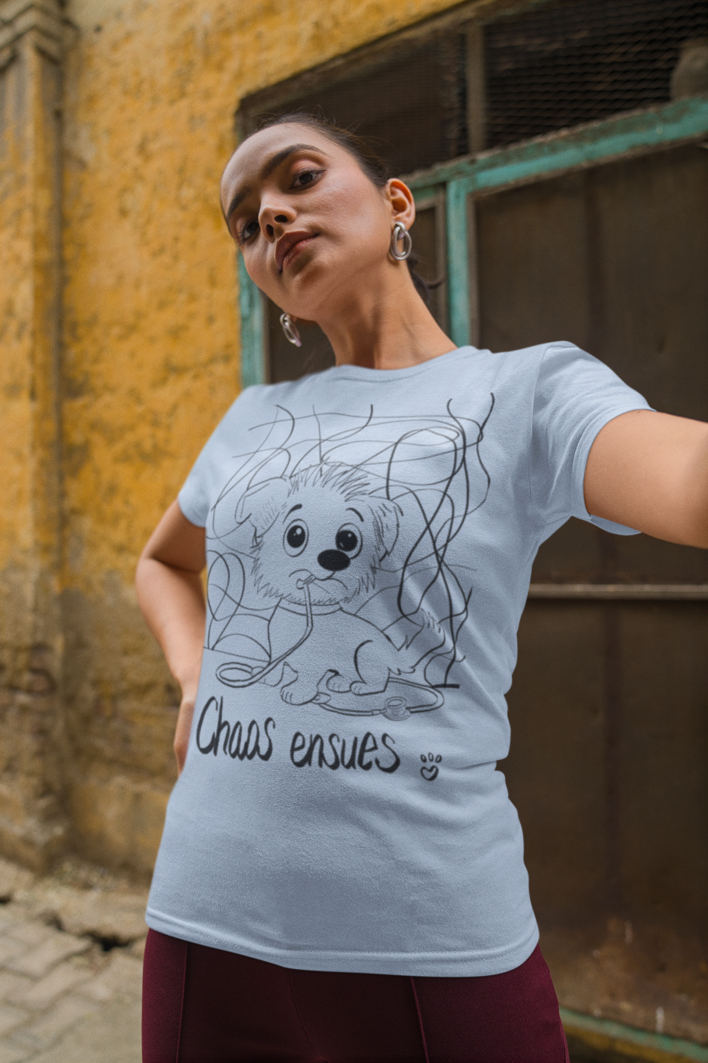 Woman with dark hair and earrings wearing light blue Chaos Ensues t-shirt taking a selfie