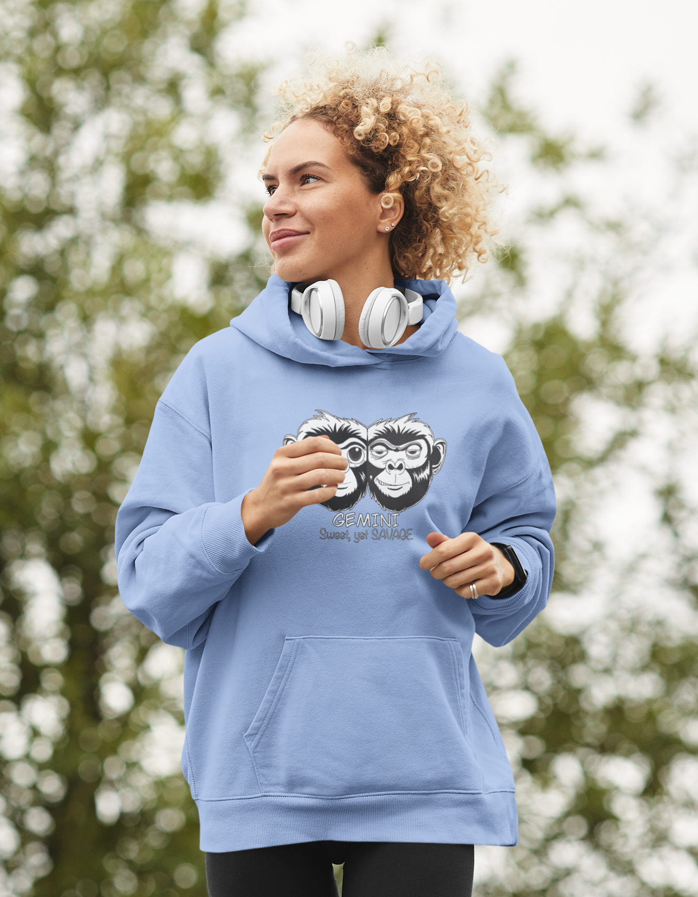 Woman with curly blonde hair wearing headphones and a carolina blue Gemini hoodie outdoors